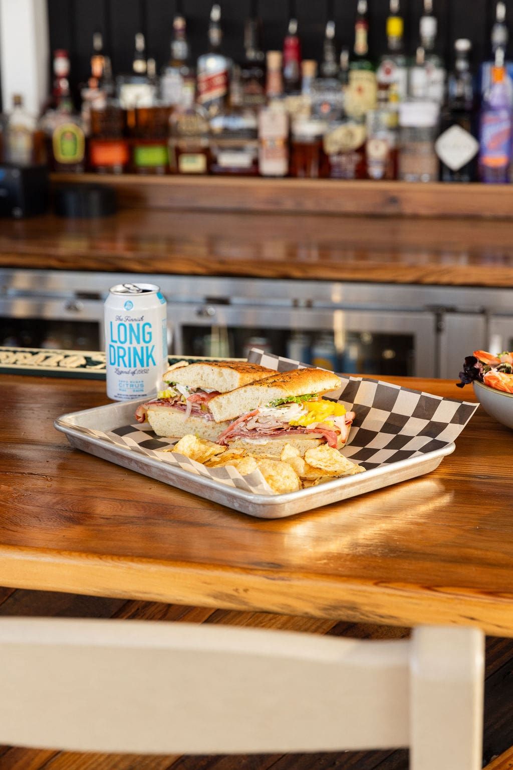 A grilled sandwich with fries and a canned drink at the bar counter