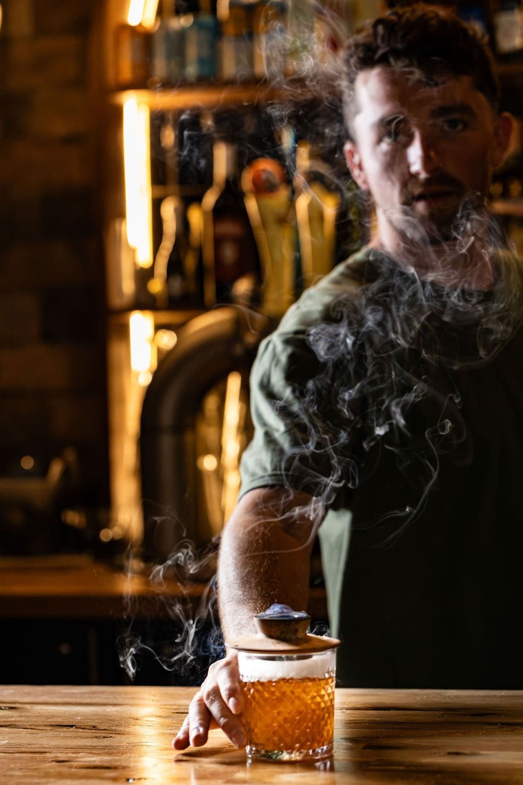 A guest at the bar with a cocktail in warm ambient light